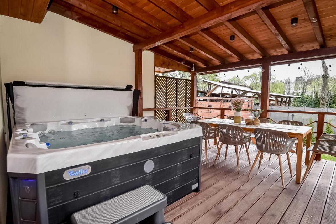 Jacuzzi na zadaszonym tarasie obok stołu z krzesłami